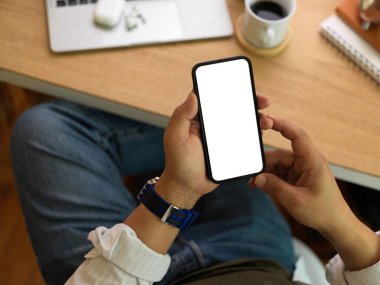 İş adamının akıllı telefon kullanarak çalışma alanının üstündeki ekranı taklit ettiği bir görüntü.