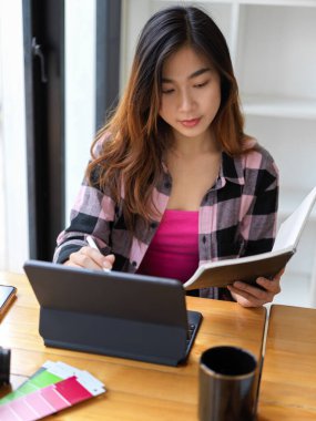 Not defteri olmayan ve kütüphanede dijital tablette çalışan genç kız öğrencinin en iyi görüntüsü