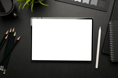 Dijital tabletli yaratıcı düz çalışma alanının en üst görünümü siyah masa üzerindeki kırpma yolunu ve malzemeleri içerir