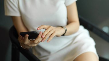 Koltukta rahatça otururken akıllı telefon kullanan kadın ellerini kapat.