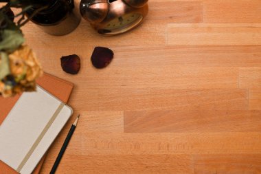 Kitap, kalem, alarm saati, vazo ve tahta masa üzerindeki kopyalama alanı ile yaratıcı düz çalışma alanı, üst görünüm