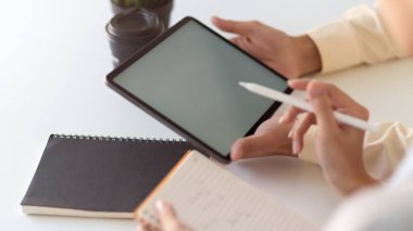 Beyaz masadaki işlerini tartışırken iki ofis çalışanının taklit tablet kullanışının görüntüsünü kapat