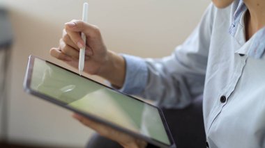 Ofis odasında dijital tabletle projesinde çalışan genç bir kadının yakın görüntüsü