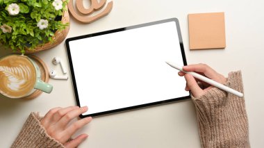Beyaz masa üzerinde stilus kalem ile dijital tablet kullanarak kadın ellerinin genel görüntüsü, kırpma yolunu da içerir