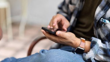 Scott ceketli bir adamın açık havada otururken akıllı telefon kullandığı görüntüyü kapat.