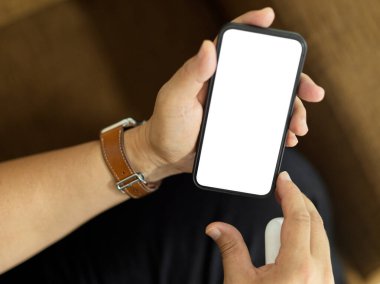 Kanepede oturan ve elinde akıllı telefon tutan bir adamın üst görüntüsü ekran kırpmayı da içeriyor