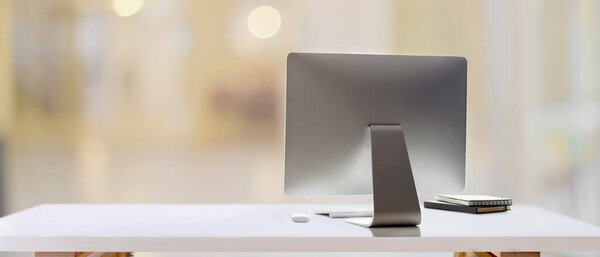 Cropped shot of white table with computer device and copy space in blurred background