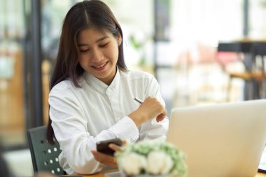 Modern çalışma alanında çalışırken gülümseyen genç bayan işçinin portresi