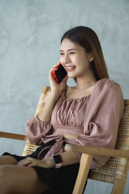 Kafede rahatça otururken telefonla konuşan kadın ofis çalışanının portresi.