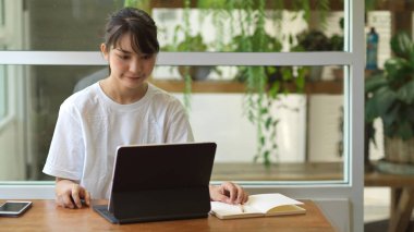 Kafedeki dijital tablet üzerinde ödev yapan genç kız öğrencinin portresi