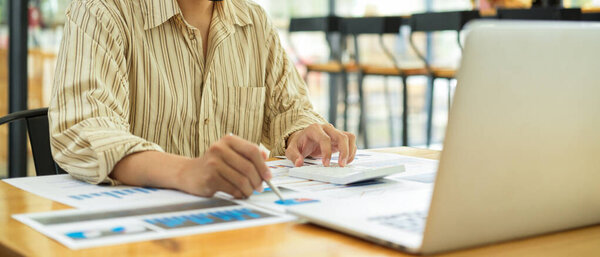 Обрезанный снимок предпринимателя, работающего с деловыми документами и ноутбуком на деревянном столе