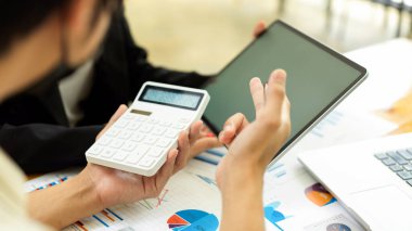 İşadamlarının ofis odasında kağıt işleri ve hesap makinesiyle projelerine danışmanlık yapmalarına yandan bakıyorum.