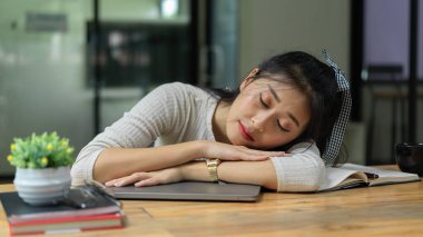 Portrait of young female student take a nap while doing assignment in living room