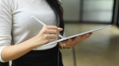 Cropped shot of female hand using digital tablet while standing in office working space