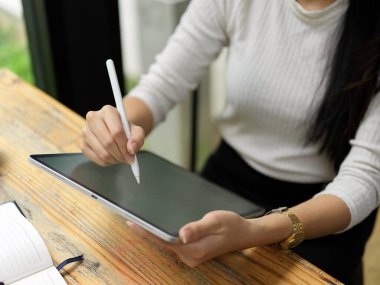 Top view of female hand using digital tablet with stylus pen to do homework 