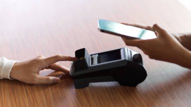 Müşteri ödeme için internet bankacılığı başvurusu yapıyor ve ödeme terminalinden ahşap masaya bir fatura alıyor.