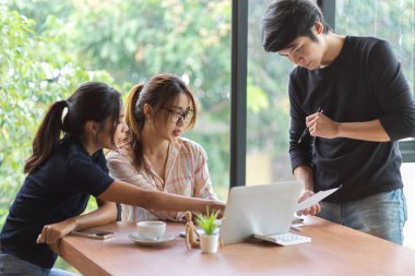 Toplantı odasında finansal rapor, dizüstü bilgisayar, ahşap masa ve ofis malzemeleriyle tartışıp beyin fırtınası yapan çalışanların portresi