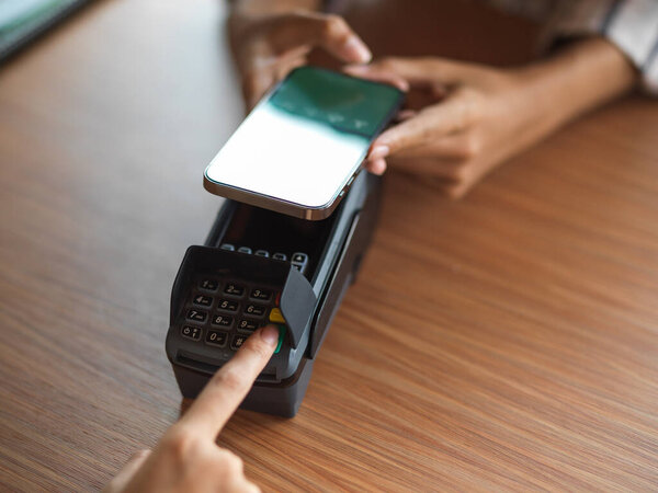 Top view of using payment terminal via smartphone QR code scanning on the wooden desk
