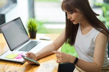 Kadın serbest çalışan, aylık giderlerini akıllı telefondan, kredi kartından, nakit ödeme konseptinden online ödeme başvurusuyla ödüyor.