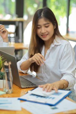 Ofiste medya raporları ve dizüstü bilgisayarla sosyal medya nişan tablosuna bakan güzel bayan medya asistanı