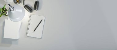 Kitap, kalem, kulaklık, masa lambası ışığı, markalarınız için fotokopi alanı olan yaratıcı masa, üst görünüm, 3D görüntüleme, 3D illüstrasyon içeren en az çalışma alanı.