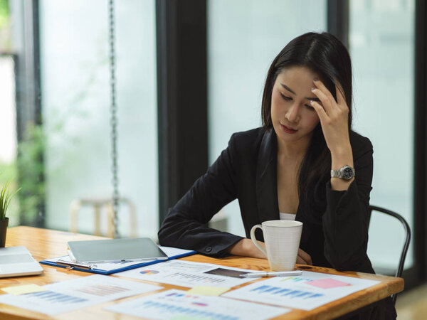 Businesswoman thinking and stressing out about business plan for next year with business reports, tablet on table, attractive businesswoman 
