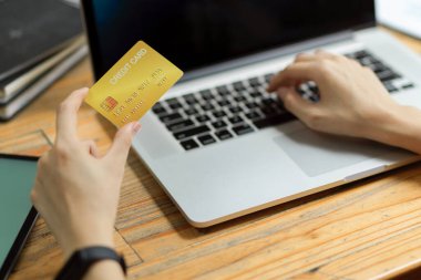 Bilgisayarda el bilgisayarında ödeme yapan, kredi kartı tutan, e-bankacılık hizmeti yoluyla laptopta ödeme yapan kadınları kapatın.