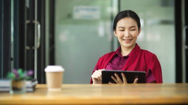 İş kadını, icra kurulu başkanı, akıllı tabletle ofiste oturup iş devrini okuyor.