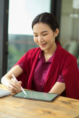 Çekici kadın İcra Sekreteri toplantıda dijital tablet, ahşap masa ve ofisteki listeyi tutuyor.