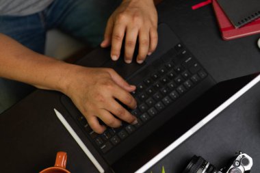 Genel plan, sıradan görünümlü işadamı hafta sonları kahve dükkanında çalışıyor, taşınabilir tablet üzerinde yazıyor, siyah arka plan