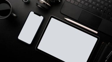 Fotoğrafçı çalışma masası konsepti, boş ekran tableti ve akıllı telefon modeli. Kamera, dizüstü bilgisayar, siyah arka planda kahve.