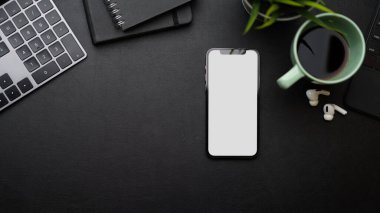Siyah arkaplan, klavye, planlama kitapları, bitki, kahve, kulaklıklar üzerindeki metin resminiz için boş alanı olan akıllı telefon boş ekran modeli