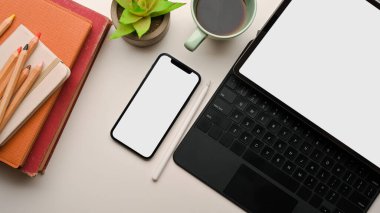 Taşınabilir tablet modeli, akıllı telefon modeli, kahve, kırtasiye malzemesi, beyaz arka planda bitki olan taşınabilir ofis masası.