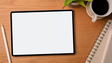 Üniversite öğrencisi modern ve rahat çalışma alanı ahşap arka plan, dijital tablet ekran modeli, stil kalem, not defterleri, sade kahve, bitki ile dekore edilmiş. Genel görünüm, kapat