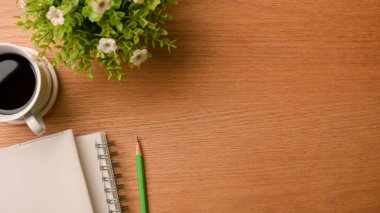 Üst görünümde basit çalışma masası, metin veya ürünün için kopyalama alanı, boş defter, kalem, sade kahve, demlikte bitki, çalışma masası, günlük, ahşap arkaplan