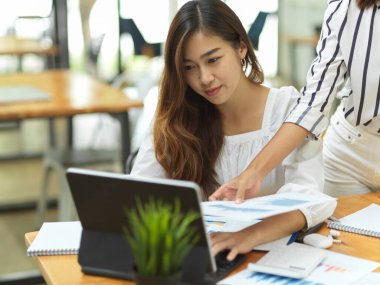 Başarılı iş kadını asistanına iş yerinde, laptopta, iş belgelerinde öğretiyor ve rehberlik ediyor.