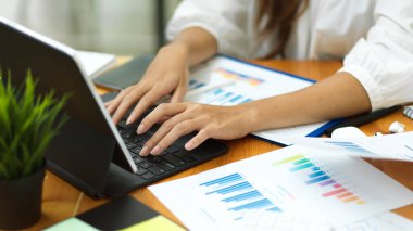 Kapalı iş kadını elleri, akıllı tablet ve finansal belgelerle çalışmak, tablet ve ofis formlarını doldurmak.