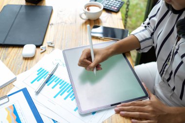 İş kadını dijital tablet kullanıyor, mali grafik raporu çalışma masasında, stilus kalem tutuyor, tablet üzerinde çizim yapıyor.