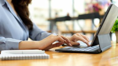 İş kadını taşınabilir tablet kullanıyor, kahve dükkanında taşınabilir klavyeye yazıyor.