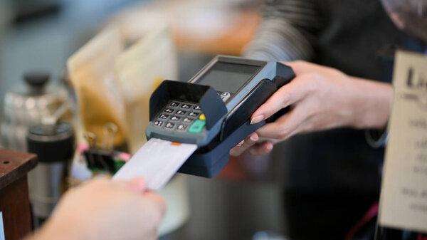 Closeup image of customer insert credit card in payment machine to pay coffee drink at coffee shop, contactless