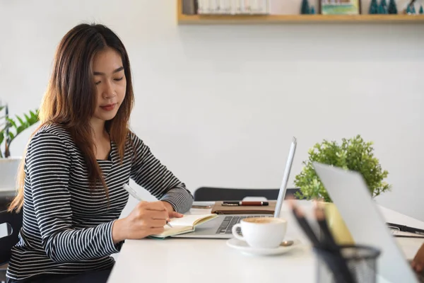 Kobieta Freelancer Skoncentrowany Pracy Robienie Notatek Pomocą Przenośnego Laptopa Kawiarni — Zdjęcie stockowe