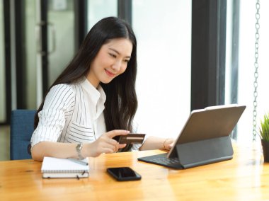 Çevrimiçi alışveriş, e-ticaret konsepti, dijital tablet kullanarak kredi kartıyla ödeme yapan genç çekici kadın.