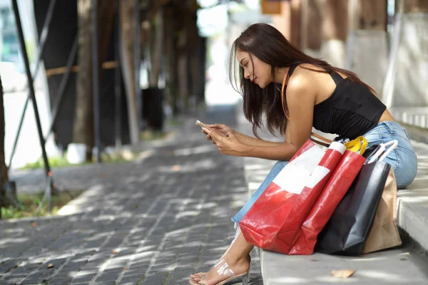 Telefonu Kullanan Genç Bir Kadın Mağazanın Merdivenlerinde Oturmuş Alışveriş Sonrası — Stok fotoğraf