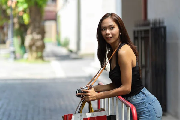 Aantrekkelijke Aziatische Vrouwelijke Toerist Met Retro Camera Boodschappentassen Leunend Barrière — Stockfoto