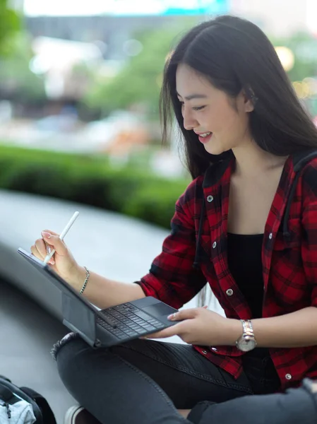 年轻的女自由职业者在城市公园用手写笔操作数字平板电脑 大学生在阳光明媚的日子在公园用平板电脑放松一下 — 图库照片