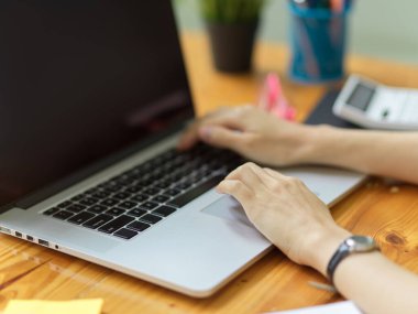 Ofisteki ahşap masadaki dizüstü bilgisayarın klavyesine dizüstü bilgisayarın el yazısını, laptopun siyah ekran modelini, taşınabilir dizüstü bilgisayar kullanan iş kadınının el yazısını kapat.