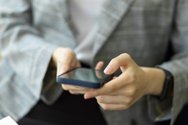 İş kadını uzaktan kumanda ve iş bağlantıları için akıllı telefon kullanıyor. Kadınların elleri online alışveriş ve sosyal ağ kurmak için cep telefonu kullanır. Resmi kapat.