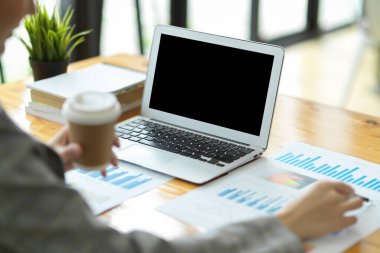 Satış performansını analiz ederek iş stratejisi planlayan genç iş kadınlarının yakın plan görüntüsü. rapor kağıtları ve masadaki dizüstü bilgisayar