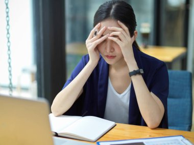 Ofisteki masasında çalışan düşünceli iş kadınları çalışmaktan, baş ağrısından, depresyondan, iş sorunlarını çözecek çözümler bulmaktan bıktılar. 