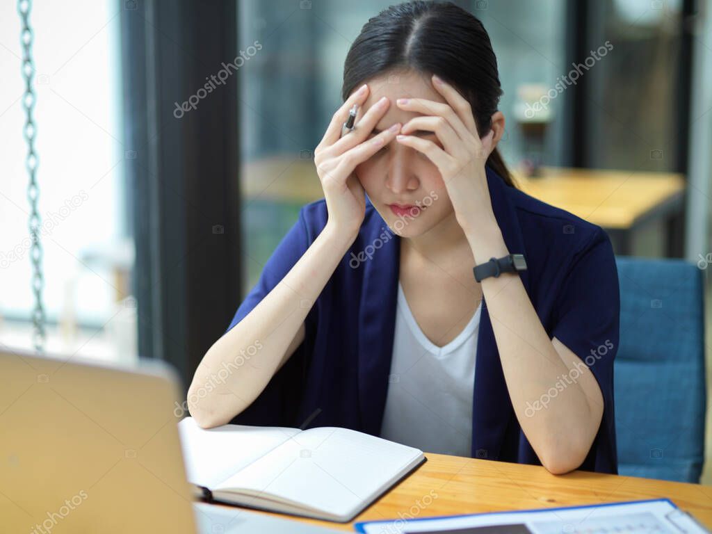 Thoughtful businesswomen working on her desk in office and feel tired of work, headache, depression, tired to find solutions to fix business problems, stressed 